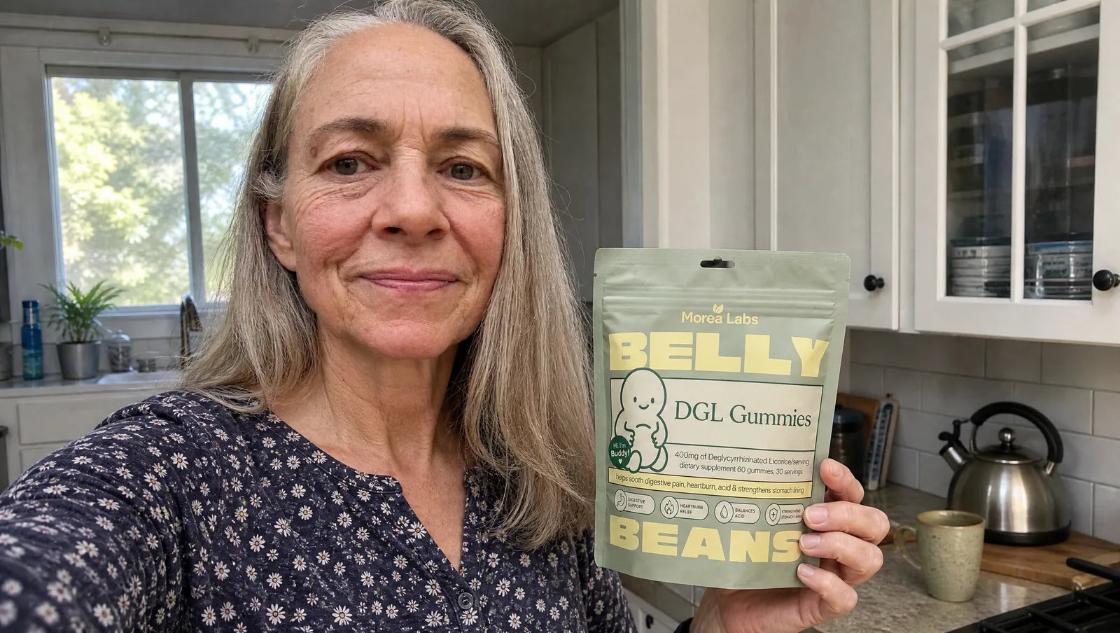 Woman in her sixties holding Belly Beans DGL gummies in her kitchen